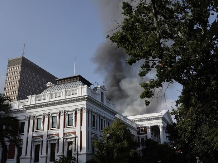 Smoke billows from the roof of a building at the South African Parliament precinct in Cape Town on January 2, 2022, during a fire incident. (Photo by Marco Longari / AFP)