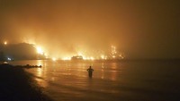 Seorang pria menyaksikan kebakaran hutan mendekati pantai Kochyli dekat desa Limni di pulau Evia, sekitar utara Athena, Yunani pada 6 Agustus 2021. AP/Thodoris Nikolaou