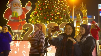 Orang-orang berpose dengan pohon Natal dan patung 2022 saat merayakan tahun baru di Kairo, Mesir, Jumat, 31 Desember 2021. AP/Amr Nabil