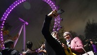 A couple take a selfie with the London Eye in background as they gather on the south bank of river Thames to celebrate New Years Eve in London, Friday, Dec. 31, 2021. In Britain, where the highly contagious variant of the coronavirus has sent caseloads soaring to record highs, Health Secretary Sajid Javid said Monday no further restrictions will be introduced in England before the new year.(AP Photo/Alberto Pezzali)