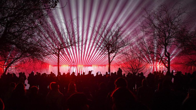 People watch a laser show during New Years celebrations in Bucharest, Romania, Saturday, Jan. 1, 2022. Thousands gathered by a lake to attend a concert and watch fireworks and a laser show during New Years celebrations in the Romanian capital. (AP Photo/Andreea Alexandru)