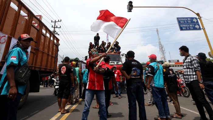 Sejumlah truk diparkir di jalan saat aksi demonstrasi Konfederasi sopir logistik Indonesia -Banyuwangi di depan pintu masuk Pelabuhan Ketapang, Banyuwangi, Jawa Timur, Selasa (3/1/2021). Unjuk rasa para sopir yang menyampaikan aspirasi terkait penerapan kebijakan zero ODOL (Over Dimensi Over Load) itu mengakibatkan aktivitas bongkar muat pelabuhan terganggu karena pintu masuk dan keluar pelabuhan tertutup truk pendemo. ANTARA FOTO/Budi Candra Setya/aww.
