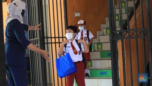 Sejumlah siswa-siswi mengikuti Pembelajaran Tatap Muka (PTM) di Sekolah Dasar Negeri (SDN) 01 Pondok Labu, Jakarta Selatan, Senin (3/1/2022). Pemerintah Provinsi (Pemprov) DKI Jakarta resmi menerapkan Pembelajaran Tatap Muka (PTM) dengan kapasitas 100 persen di seluruh sekolah mulai hari Senin (3/1). Relaksasi kebijakan ini sesuai dengan kondisi PPKM Level 1 yang diterapkan di Jakarta. Kepala bidang kesiswaan SD 01 Muhamad Nasir mengatakan, kebijakan tersebut merefleksikan Surat Keputusan Bersama (SKB) 4 Menteri yang diputuskan pada 21 Desember 2021. SKB dengan Nomor Nomor 05/KB/2021, Nomor 1347 Tahun 2021, Nomor HK.01.08/MENKES/6678/2021, Nomor 443-5847 Tahun 2021 berisi tentang Panduan Penyelenggaraan Pembelajaran di Masa Pandemi Covid-19. Meski dibuka 100 persen, Sekolah mewajibkan semua warga sekolah untuk menerapkan protokol kesehatan secara ketat. Terlebih lagi bagi mereka yang belum divaksinasi. Kebijakan PTM juga disambut baik bagi orang tua murid, Yulia salah satu orang tua murid kelas 2 mengatakan senang setelah dibuat PTM 100%. 