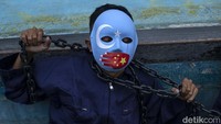 Para peserta aksi menggunakan topeng dan rantai.