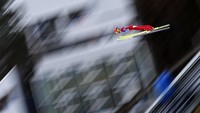 Atlet Austria, Philipp Aschenwald terbang di udara saat melakukan lompatan kedua di etape ketiga dalam kejuaraan Empat Bukit ke-70 di Innsbruck, Austria (3/1/2021).