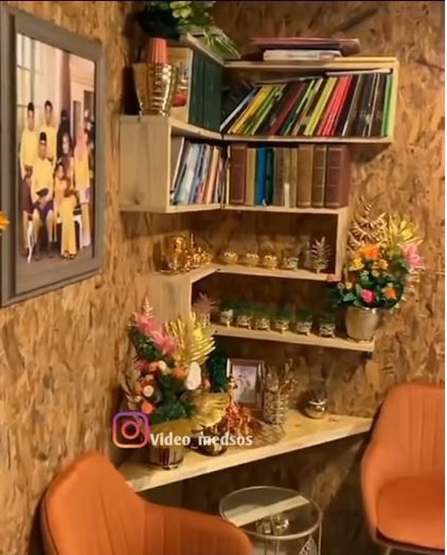 Bagian dalam rumah yang didominasi oleh warna coklat keemasan itu juga memiliki rak dinding untuk menyimpan buku-buku. Di samping rak dinding tersebut terpajang foto keluarga sang pemilik rumah. Foto: Instagram/@video_medsos
