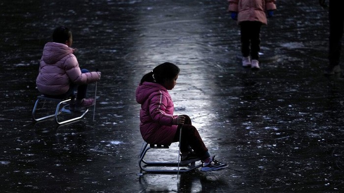 Children play ice skating on a frozen river near a residential area during the New Year holiday in Beijing, Monday, Jan. 3, 2022. (AP Photo/Andy Wong)