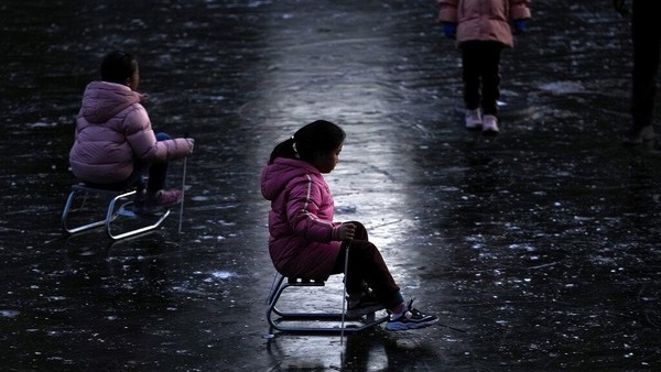 Anak-anak bermain ice skating di sungai yang membeku di dekat permukiman warga selama liburan Tahun Baru di Beijing, Senin, (3/1/2022). AP/Andy Wong.