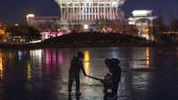 Warga menarik seorang anak melintasi danau beku dekat Olympics Green di Beijing, China. AP/Ng Han Guan.