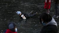Seorang anak jatuh saat bermain di sungai beku dekat pemukiman warga saat libur Tahun Baru di Beijing. AP/Andy Wong.