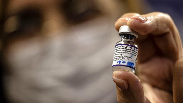 An Israeli medical worker poses with a vial of the Pfizer-BioNTech COVID-19 vaccine at the Sheba Medical Center in Ramat Gan, Israel, where people are receiving a fourth dose Friday, Dec. 31, 2021. (AP Photo/Tsafrir Abayov)