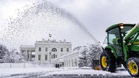 Seorang penjaga halaman membersihkan jalan masuk di depan Sayap Barat Gedung Putih di Washington.