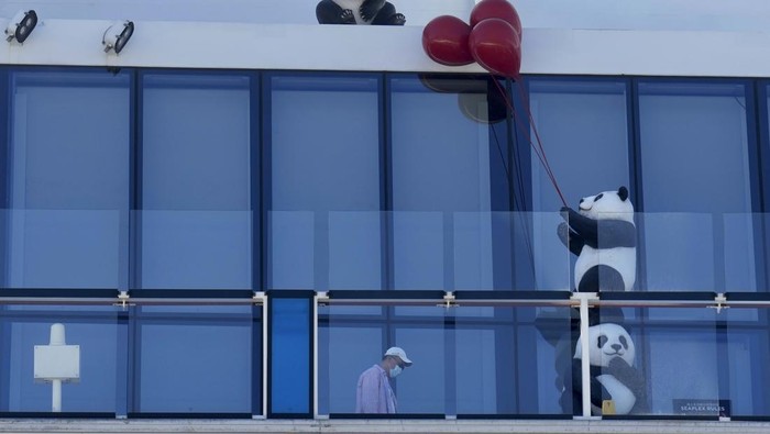 Passengers look out from the Spectrum of the Seas cruise ship docked at Kai Tak cruise terminal in Hong Kong Wednesday, Jan. 5, 2022. Thousands of passengers were being held Wednesday on the cruise ship in Hong Kong for coronavirus testing after health authorities said nine passengers were linked to a recent omicron cluster and ordered the ship to turn back. (AP Photo/Vincent Yu)