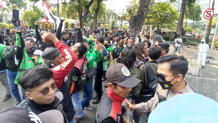 Massa driver ojol bergerak menuju Istana Negara di Jalan Medan Merdeka Utara, Jakarta. Namun massa tertahan kawat besi di Jalan Medan Merdeka Barat. (Wildan N/detikcom)