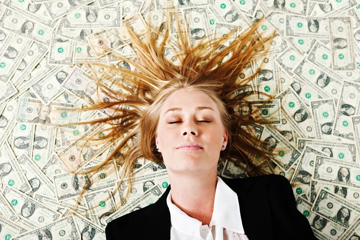 A pretty young blonde smiles in her sleep as she naps on a pile of many US dollars. If her dreams come true shell be a very wealthy young lady!