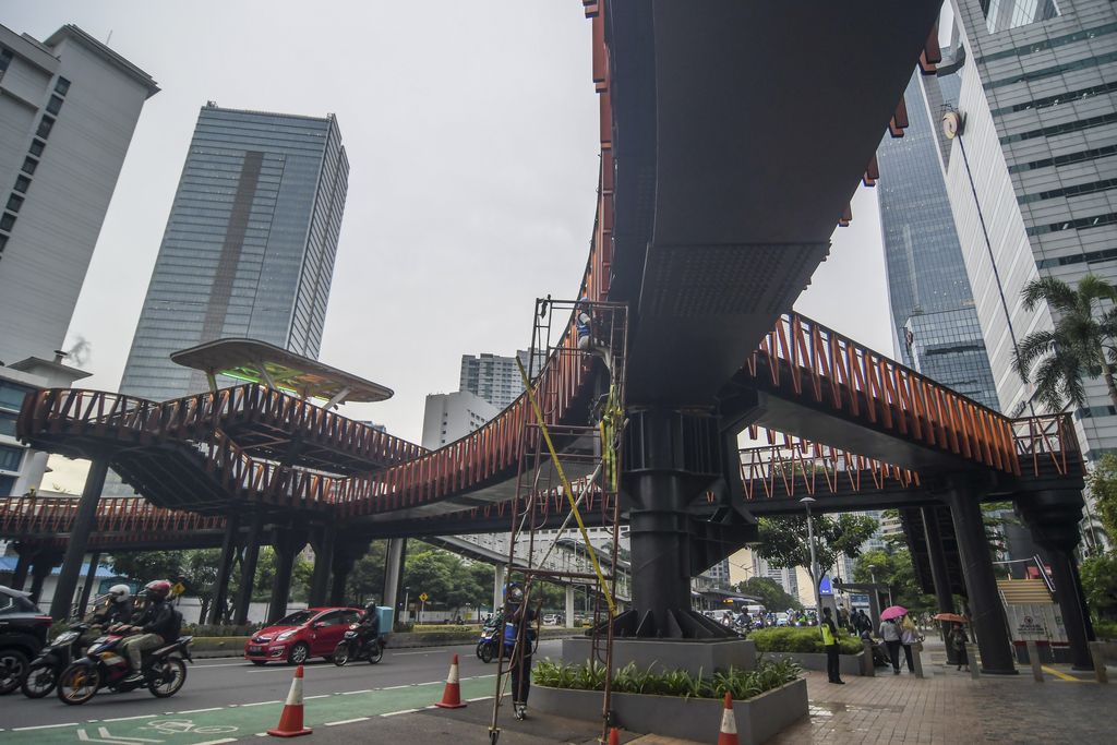 Warga melintas disamping proyek jembatan penyebrangan orang (JPO) Pinisi di kawasan Sudirman, Jakarta, Kamis (6/1/2022). JPO berkonsep Kapal Pinisi saat ini progresnya sudah mencapai 98 persen dan memasuki tahap penyelesaian akhir. ANTARA FOTO/Galih Pradipta/foc.
