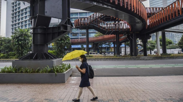 Warga melintas disamping proyek jembatan penyebrangan orang (JPO) Pinisi di kawasan Sudirman, Jakarta, Kamis (6/1/2022). JPO berkonsep Kapal Pinisi saat ini progresnya sudah mencapai 98 persen dan memasuki tahap penyelesaian akhir. ANTARA FOTO/Galih Pradipta/foc.