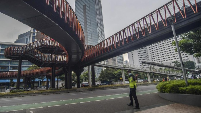 Warga melintas disamping proyek jembatan penyebrangan orang (JPO) Pinisi di kawasan Sudirman, Jakarta, Kamis (6/1/2022). JPO berkonsep Kapal Pinisi saat ini progresnya sudah mencapai 98 persen dan memasuki tahap penyelesaian akhir. ANTARA FOTO/Galih Pradipta/foc.