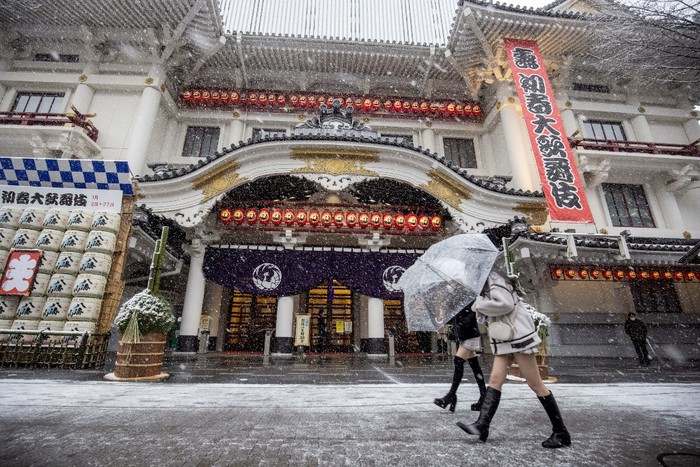 Pedestrians walk past the landmark Kabukiza theatre as snow falls in Tokyo on January 6, 2022. (Photo by Behrouz MEHRI / AFP)