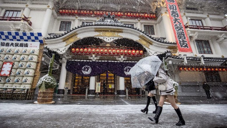 Pedestrians walk past the landmark Kabukiza theatre as snow falls in Tokyo on January 6, 2022. (Photo by Behrouz MEHRI / AFP)
