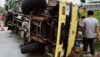 Truk terbanting ke kiri dan terguling.