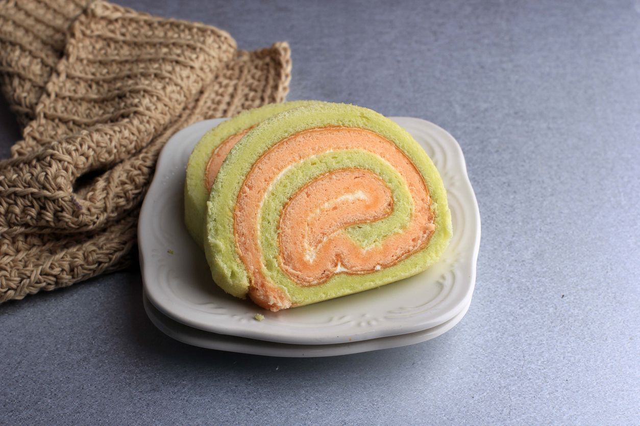Bolu Gulung or Roll Cake Pandan and Strawberry with Vanilla Cream. Sliced. Served on White Background, Copy Space