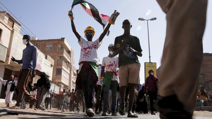People chant slogans and burn tires during a protest to denounce the October 2021 military coup, in Khartoum, Sudan, Thursday, Jan. 6, 2022. Sudanese took to the streets in the capital, Khartoum, and other cities on Thursday in anti-coup protests as the country plunged further into turmoil following the resignation of the prime minister earlier this week. (AP Photo/Marwan Ali)