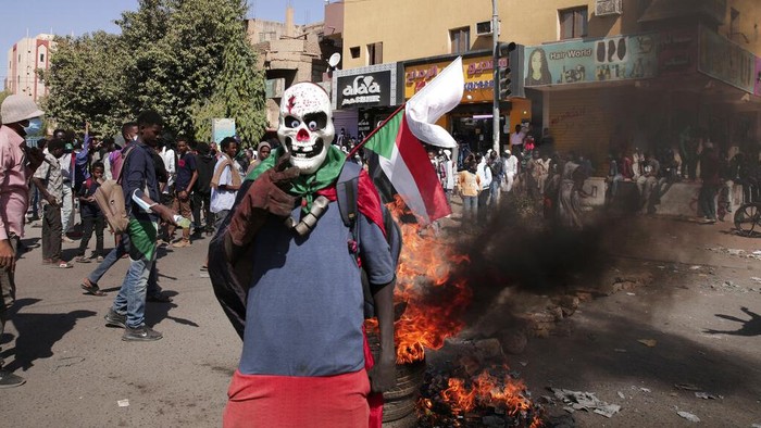 People chant slogans and burn tires during a protest to denounce the October 2021 military coup, in Khartoum, Sudan, Thursday, Jan. 6, 2022. Sudanese took to the streets in the capital, Khartoum, and other cities on Thursday in anti-coup protests as the country plunged further into turmoil following the resignation of the prime minister earlier this week. (AP Photo/Marwan Ali)