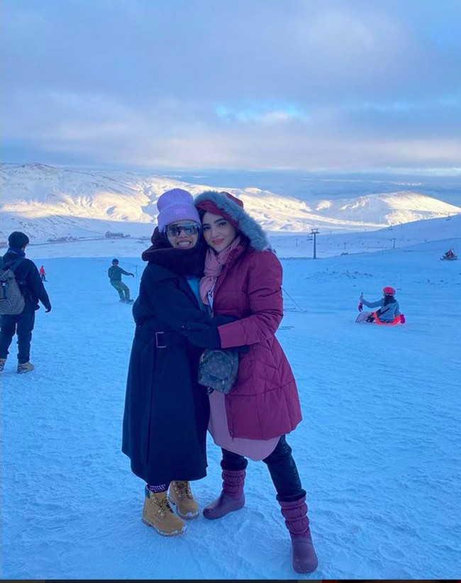 Begini gaya Ashanty foto bareng besan, Lenggogeni Faruk. Saat berada di pegunungan bersalju itu, Ashanty tampak mengenakan mantel fuschia dengan aksen berbulu dan boots berwarna senada. (Foto: Instagram/@ashanty_ash)