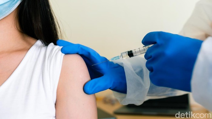 Harga Vaksin Booster Belum Ditetapkan Pemerintah, Ini 6 Hal yang Diketahui Doctors wearing PPE uniforms white gloves are inoculating the arm muscles to prevent COVID 19.