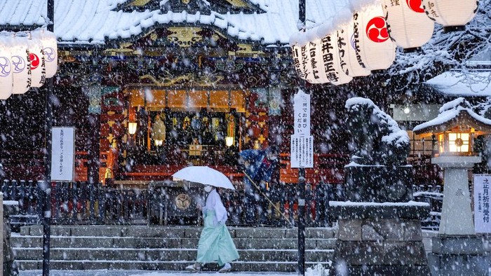 People walk across at the famed Shibuya scramble crossing as the snow comes down Thursday, Jan. 6, 2022, in Tokyo.   Japanese Foreign Minister Yoshimasa Hayashi on Thursday asked that the U.S. military in Japan stay inside its bases to prevent the further spread of COVID-19. Prime Minister Fumio Kishida said he has decided to tighten virus restrictions in Okinawa, Yamaguchi prefecture, where US bases are located, and Hiroshima.(AP Photo/Kiichiro Sato)