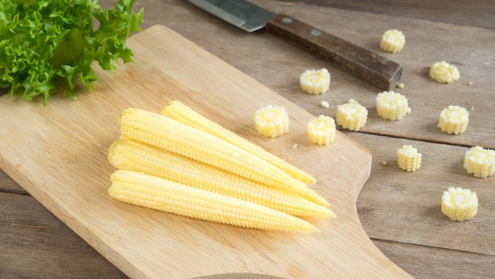 jagung muda Baby corns and knife on cutting board.