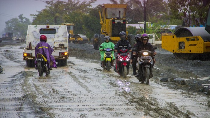 Proyek Tak Kunjung Selesai, Jalan Trans Kalimantan Bak Kubangan Pengemudi truk mengarahkan pengemudi mobil yang terjebak di jalan Trans Kalimantan yang rusak di Kecamatan Liang Anggang, Banjarbaru, Kalimantan Selatan, Jumat (7/1/2022). Proyek rehabilitasi Jalan Ahmad Yani Lianganggang Kota Banjarbaru hingga batas Kabupaten Tanah Laut yang menelan anggaran sebesar Rp74 miliar itu hingga kini tak kunjung selesai dan telah melewati batas waktu pengerjaan yang seharusnya yaitu pada 31 Desember 2021 lalu dan berdampak pada ekonomi masyarakat setempat. ANTARA FOTO/Bayu Pratama S/rwa.