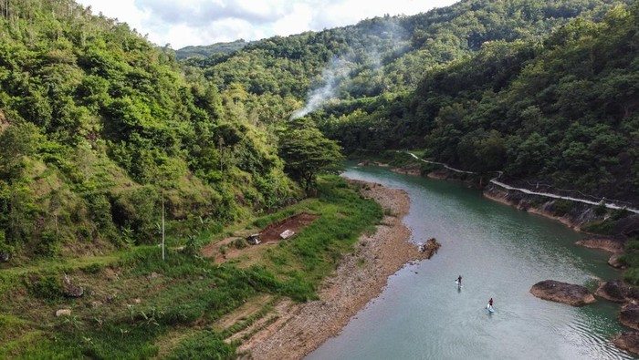 Pengunjung bermain Stand Up Paddle di Sungai Oyo, Selopamioro, Imogiri, Bantul, DI Yogyakarta, Jumat (7/1/2022). Aliran Sungai Oyo yang terletak di antara perbukitan dengan bentang alam yang indah tersebut menjadi potensi wisata alam di Kabupaten Bantul. ANTARA FOTO/Hendra Nurdiyansyah/rwa.
