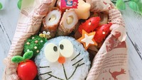 Kalau bento satu ini bentuknya Doraemon. Terdiri dari nasi yang dibentuk wajah Doraemon, sosis, fishcake isi keju dan sayuran. Untuk membuat bagian mata menggunakan keju, sementara bagian mulut dan kumis Doraemon mengandalkan nori.  Foto: Instagram @hitomi.1103