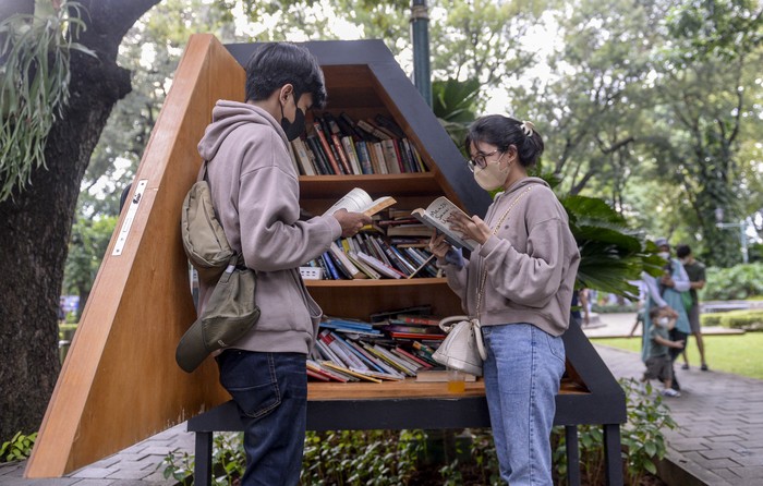 Pengunjung membaca buku di perpustakaan mini di Taman Suropati, Jakarta, Sabtu (8/1/2022). Jakarta ditetapkan sebagai City of Literature atau Kota Sastra Dunia dari 49 kota lain di dunia yang tergabung dalam jaringan kota kreatif jaringan kota kreatif dunia atau UNESCOs Creative City Network tahun 2021 oleh Badan Pendidikan dan Kebudayaan PBB (UNESCO). ANTARA FOTO/M Risyal Hidayat/rwa.