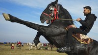 Dalam foto ini seorang pria memamerkan kemampuannya dalam berkuda selama perayaan Epiphany di desa Pietrosani, Rumania, Kamis (6/1/2022). Mengutip AP, menurut tradisi Epiphany di daerah tersebut, setelah kebaktian keagamaan, para penduduk desa memberkati kuda mereka dengan air suci kemudian bersaing dalam perlombaan. AP Photo/Vadim Ghirda.