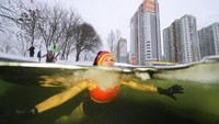 Seorang wanita tampak berenang di sebuah kolam yang dipenuhi es di St. Petersburg, Rusia, Selasa (4/1/2022). Diketahui, suhu di St. Petersburg pada saat itu adalah -7C (19F). AP Photo/Dmitri Lovetsky.