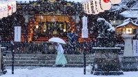 Seorang warga berjalan melewati kuil utama sementara seorang pekerja membersihkan tangga saat salju turun di kawasan Tokyo, Jepang, pada Kamis (6/1/2022). AP Photo/Kiichiro Sato.