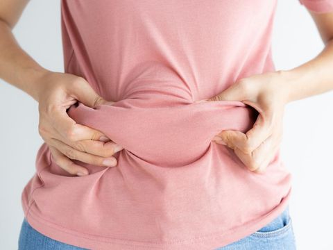 Woman hand holding her own belly fat and cellulite on white background. Women before weight loss and shape up healthy stomach muscle concept.