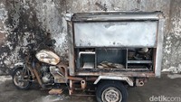 Sebuah kendaraan roda tiga juga turut terbakar parah. Tampak kendaraan pengangkut barang itu berisi perabotan seperti piring.