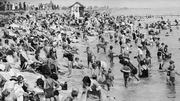 Tak sedikit pula warga yang memilih menghabiskan waktu liburan dengan bermain di pantai seperti yang terlihat di foto yang diabadikan pada tahun 1935 ini, tampak sejumlah wisatawan memenuhi pantai yang berada di Canvey Island, Essex. Fred Morley/Fox Photos/Hulton Archive/Getty Images.