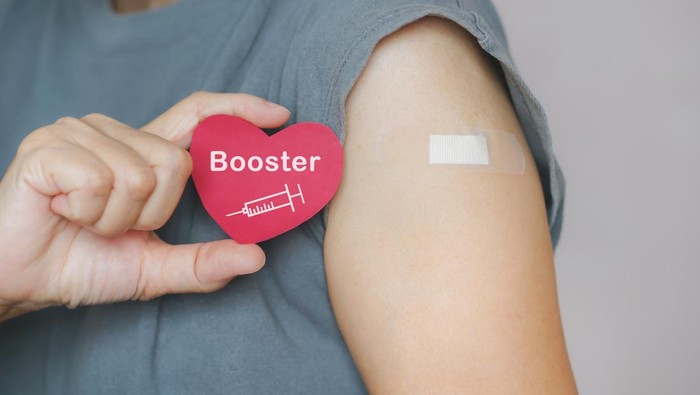 senior woman show red heart shape with syringe icon,  after vaccinated or inoculation  booster dose  due to spread of corona virus, population, social or herd immunity concept