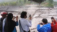 Warga mengabadikan momen material lahar hujan Gunung Semeru yang mengalir di Kali Regoyo. Lahar hujan erupsi Gunung Semeru terjadi akibat curah hujan yang tinggi di kawasan lereng gunung.