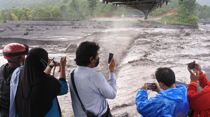 Lahar Hujan Gunung Semeru Jadi Tontonan Warga Warga melihat material lahar hujan Gunung Semeru mengalir di Kali Regoyo, Desa Sumberwuluh, Candipuro, Lumajang, Jawa Timur, Minggu (9/1/2022). Lahar hujan erupsi Gunung Semeru terjadi akibat curah hujan yang tinggi di kawasan lereng gunung, membawa material pasir, kerikil dan batu yang masih mengancam warga di sepanjang aliran sungai.
ANTARA FOTO/Seno/wsj