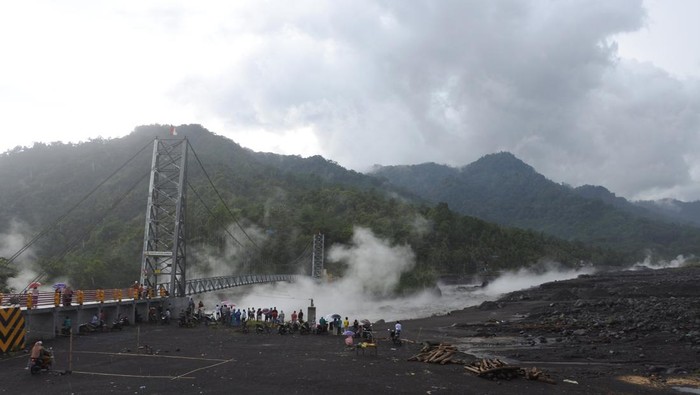 Lahar Hujan Gunung Semeru Jadi Tontonan Warga Warga melihat material lahar hujan Gunung Semeru mengalir di Kali Regoyo, Desa Sumberwuluh, Candipuro, Lumajang, Jawa Timur, Minggu (9/1/2022). Lahar hujan erupsi Gunung Semeru terjadi akibat curah hujan yang tinggi di kawasan lereng gunung, membawa material pasir, kerikil dan batu yang masih mengancam warga di sepanjang aliran sungai.
ANTARA FOTO/Seno/wsj
