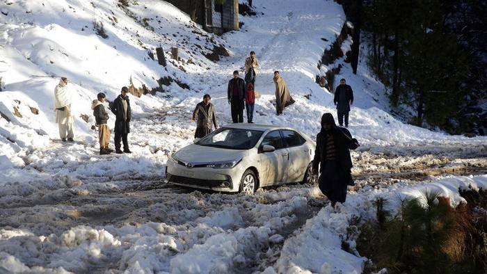A vehicle is stranded on a snow-covered road in a heavy snowfall-hit area in Murree, some 28 miles (45 kilometers) north of the capital of Islamabad, Pakistan, Saturday, Jan. 8, 2022. Temperatures fell to minus 8 degrees Celsius (17.6 Fahrenheit) amid heavy snowfall at Pakistan's mountain resort town of Murree overnight, killing multiple people who were stuck in their vehicles, officials said Saturday. (AP Photo/Rahmat Gul)