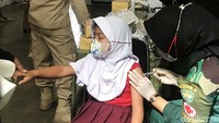 Seorang siswa SD menutup mata saat divaksin karena takut dengan jarum suntik.