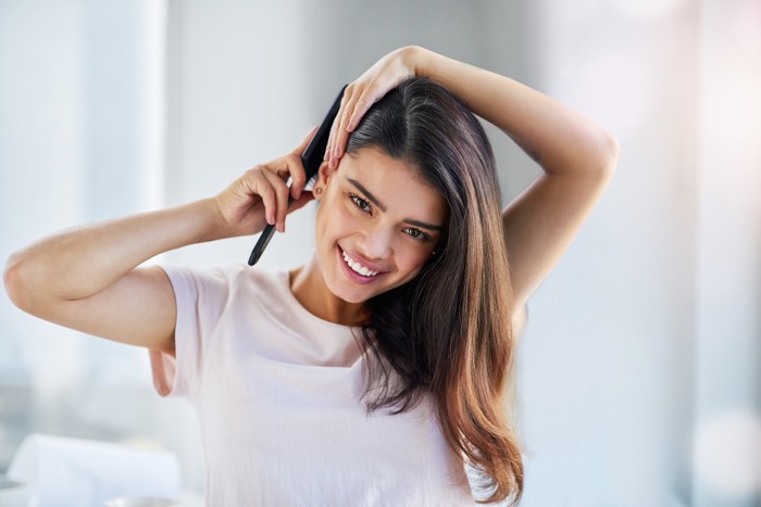 rambut Portrait of a beautiful young woman brushing her hair in the bathroom at home