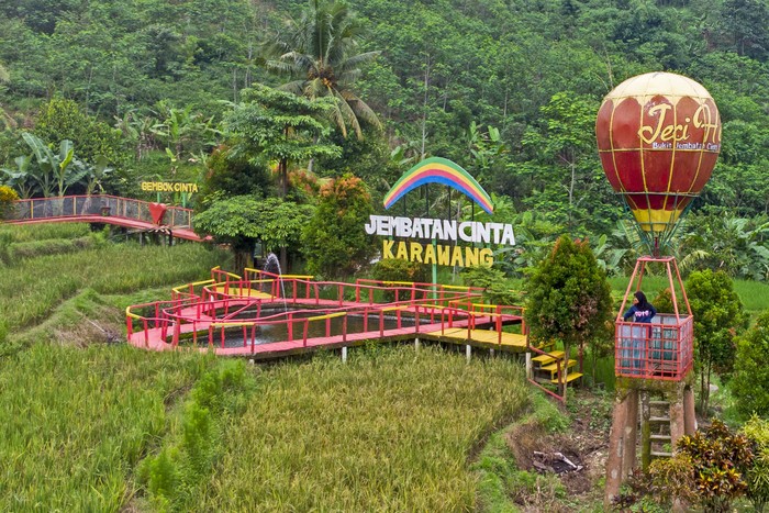 Pengunjung menikmati suasana wisata Jembatan Cinta di Desa Mekarbuana, Tegalwaru, Karawang, Jawa Barat, Minggu (9/1/2022). Menparekraf Sandiaga Uno mengatakan sektor pariwisata dan ekonomi kreatif (parekraf) dapat berkontribusi besar bagi kebangkitan ekonomi di tanah air pada tahun 2022. ANTARA FOTO/M Ibnu Chazar/foc.